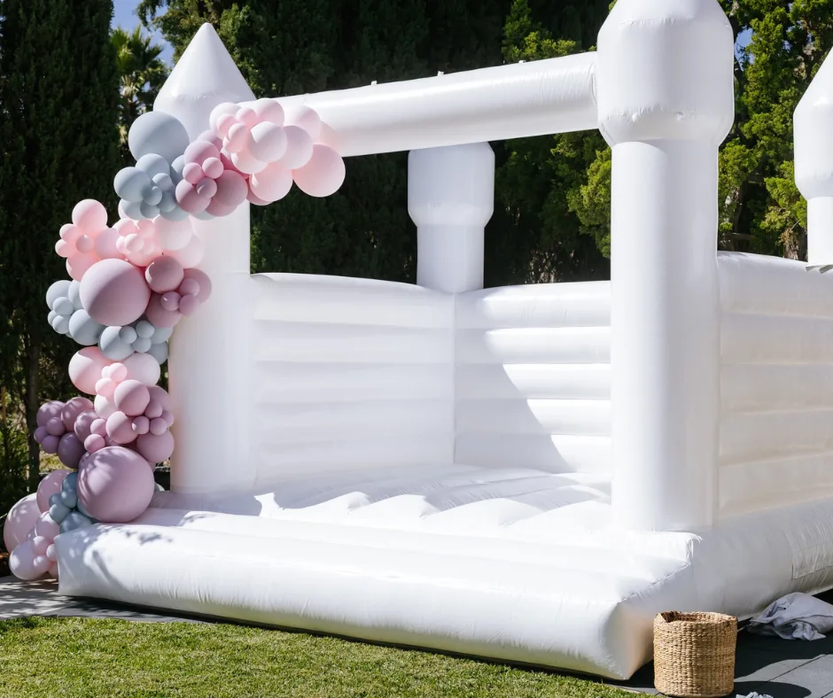 White bounce house rental with pastel balloon garland — Riverside and Orange County CA
