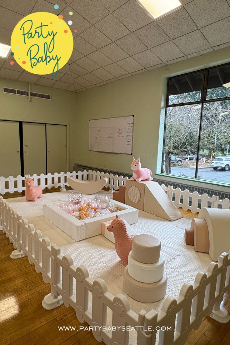 Indoor soft play birthday party setup with ball pit and foam climbers in pastel pink and white