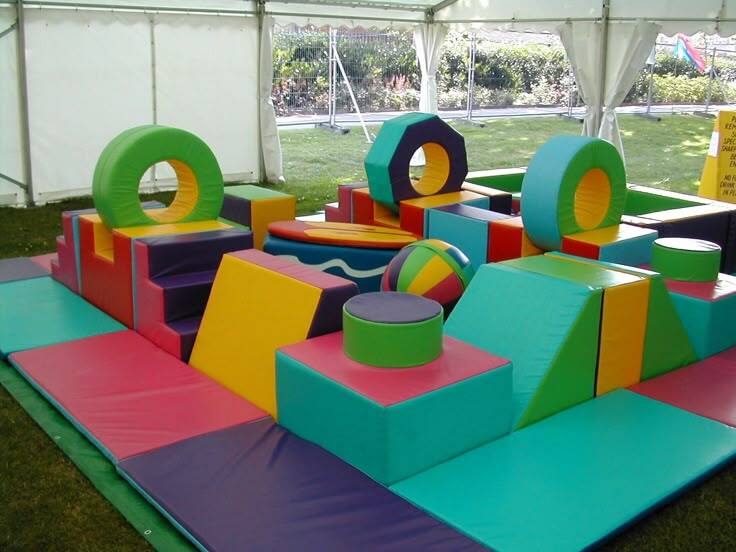 Colorful soft play rental setup under an event tent for an outdoor birthday party