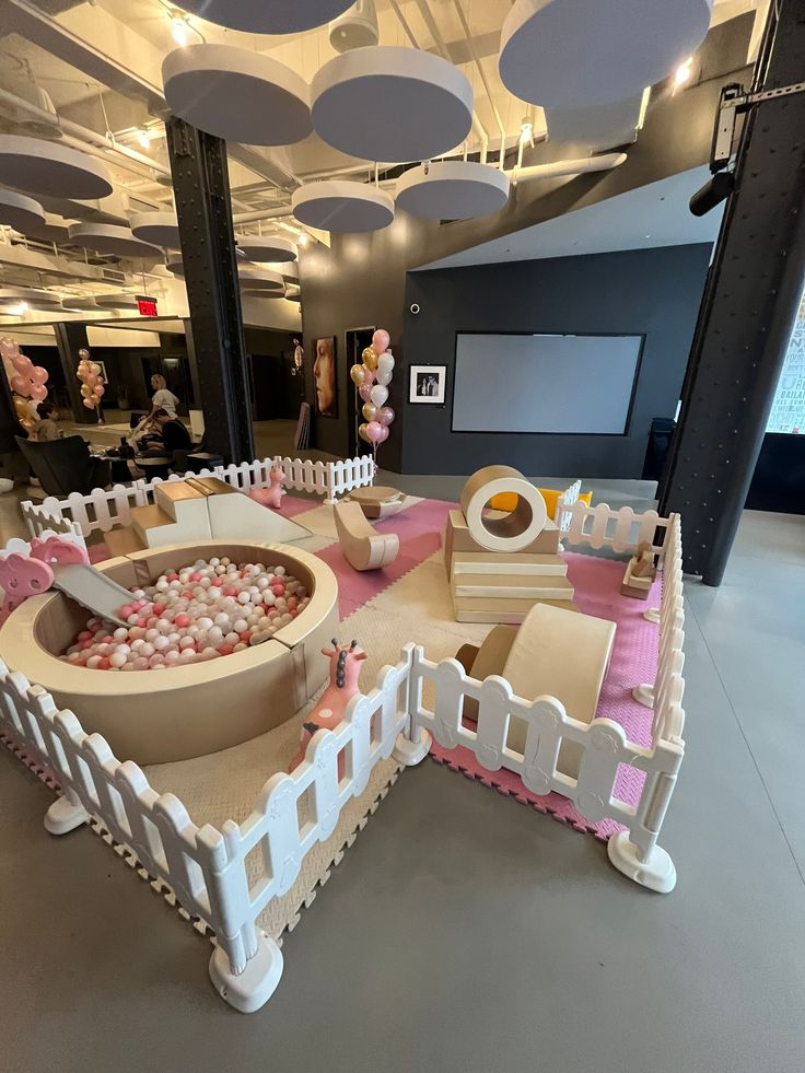 Boho soft play rental setup with ball pit, foam climbers and white picket fence for toddler birthday party